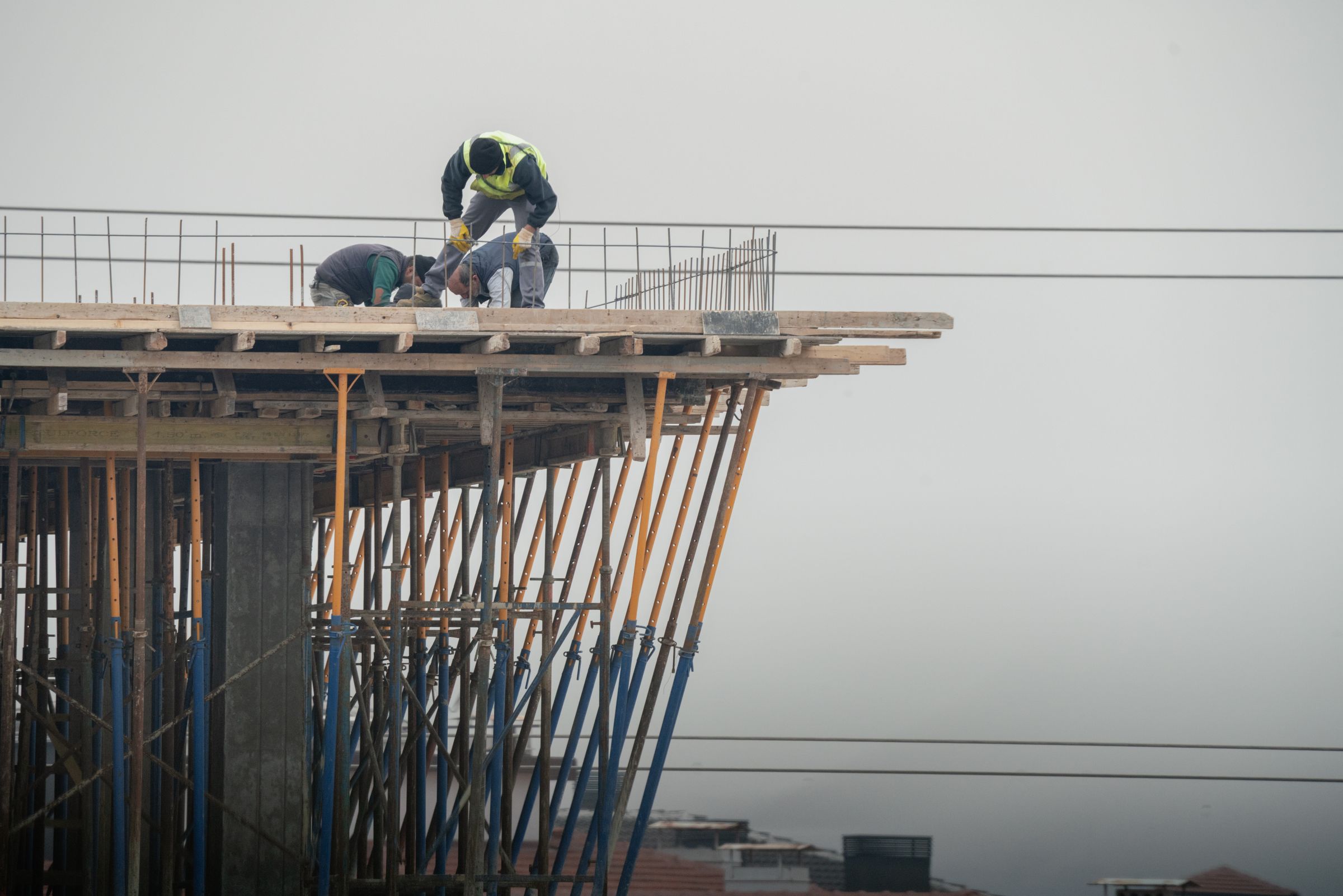 Construction workers wearing safety vests on a raised concrete deck